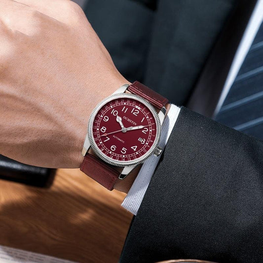 Men's automatic wristwatch with burgundy dial, silver case, and maroon fabric strap