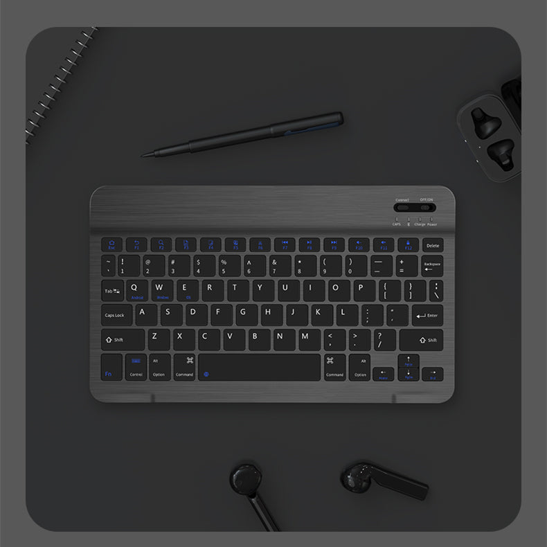 Black keyboard on a dark surface with a pen and earbuds.
