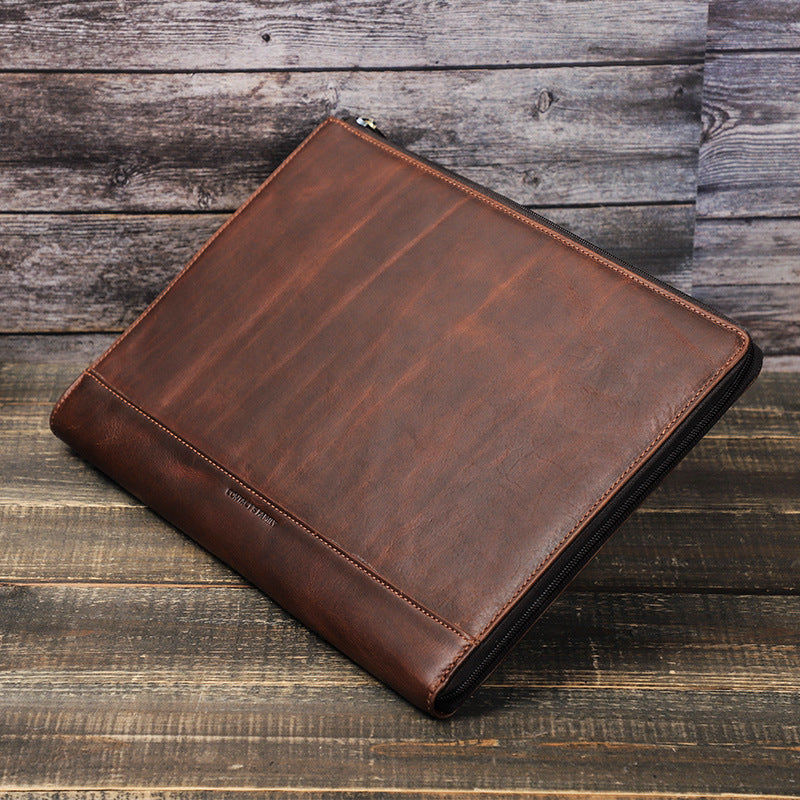 Brown leather laptop bag with stitched edges and top zipper closure, angled view