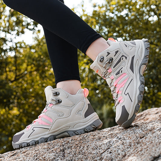 Gray hiking boots with pink accents worn by a person on a rock with a blurred natural background