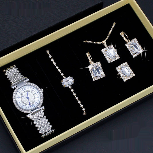 Jewelry set including a watch and earrings on a black display box with gold trim.