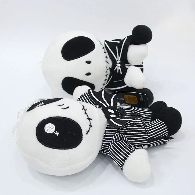 Plush doll shown lying on side, with black-and-white stripes and large bow detail.