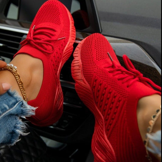 Red sneakers worn with denim shorts, sitting on a car's dashboard.