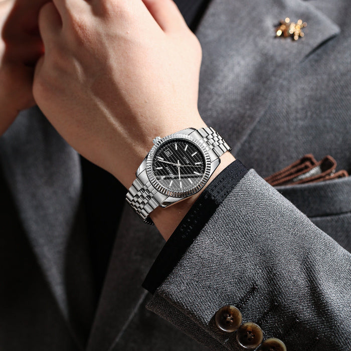 Silver watch on a person's wrist with a gray suit background