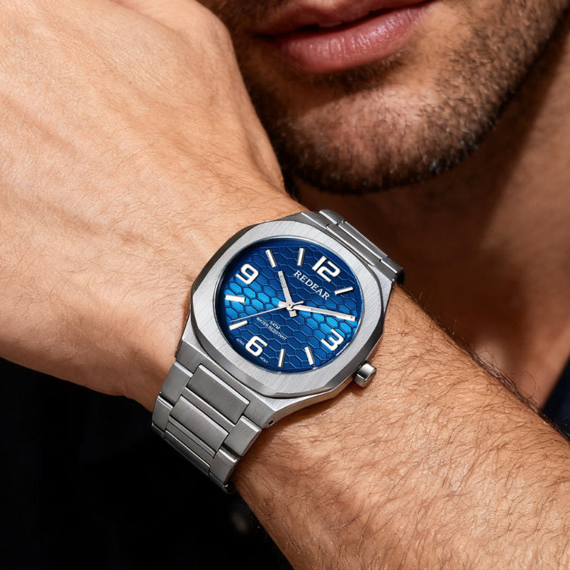 Silver watch with blue face on a wrist, close-up shot.
