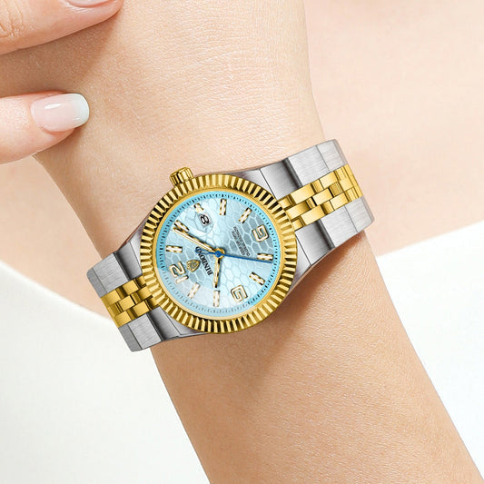 Two-tone watch with blue face on a wrist against a neutral background