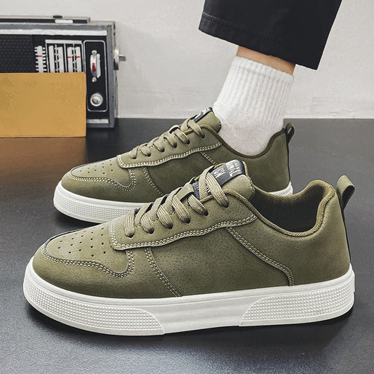 Green sneakers with white soles worn by a person on a gray surface.