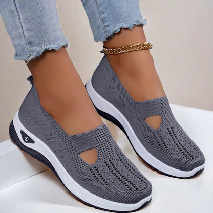 Women's Gray slip-on shoes with white soles worn with light blue jeans on a neutral background