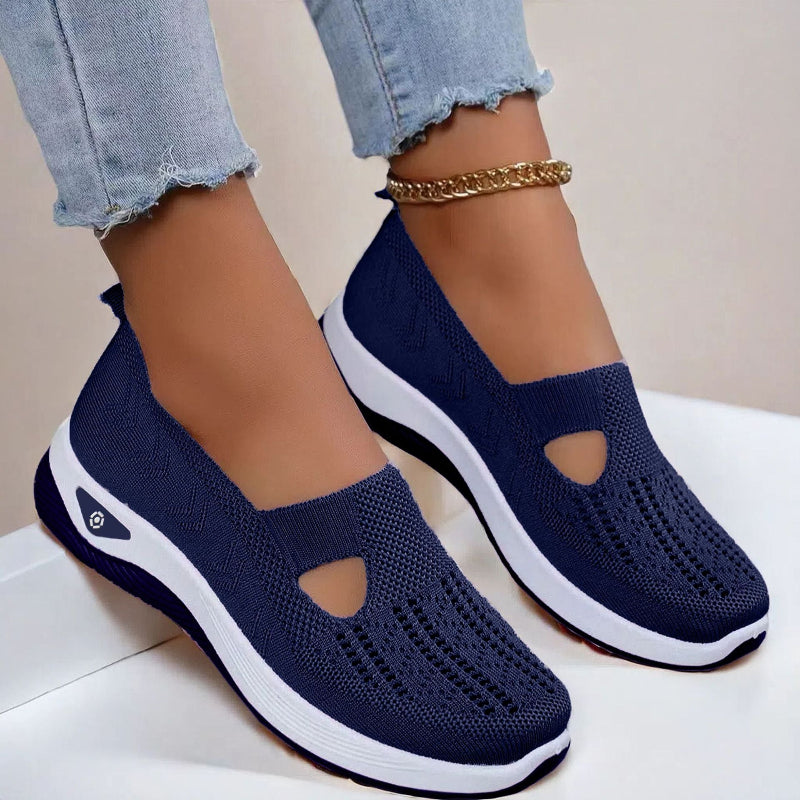 Women's Navy slip-on shoes with white soles worn with light blue jeans on a neutral background