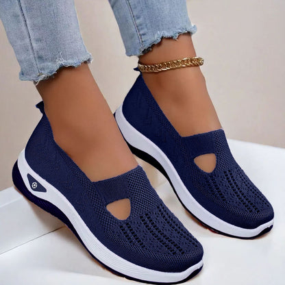 Women's Navy slip-on shoes with white soles worn with light blue jeans on a neutral background
