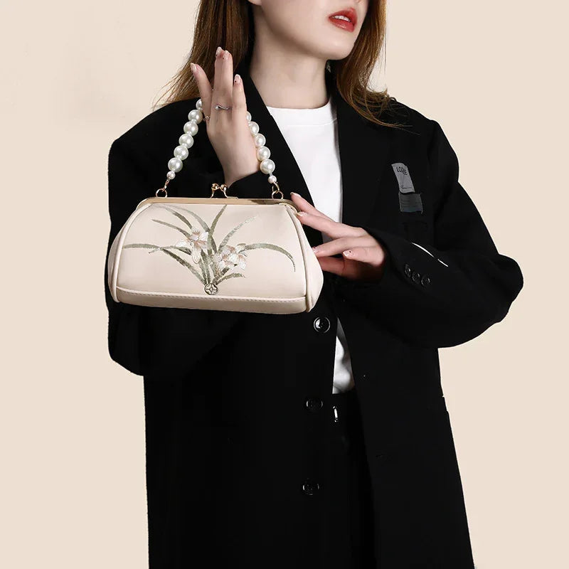 Beige embroidered shoulder bag with pearl handle and gold chain strap, floral front