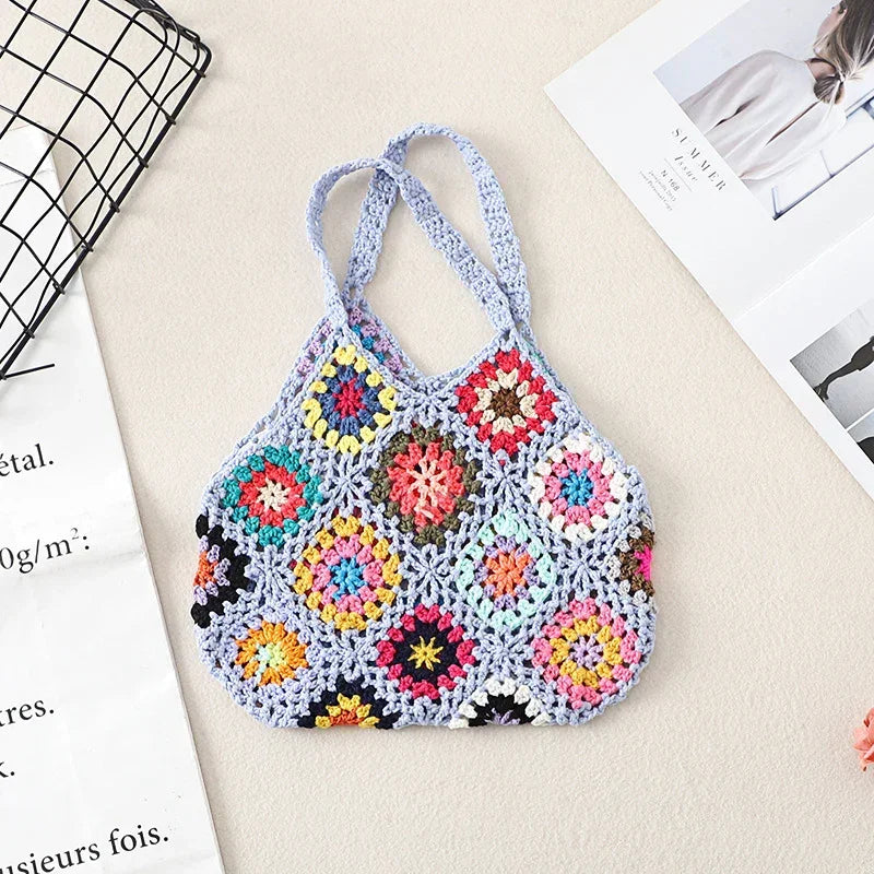 Crochet wool handbag tote with light blue base, multicolor floral granny squares, and loop handles.