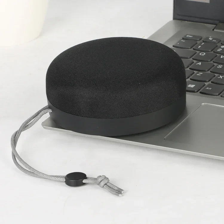 Dark grey cloth-covered Bluetooth speaker with hanging cord and rounded base