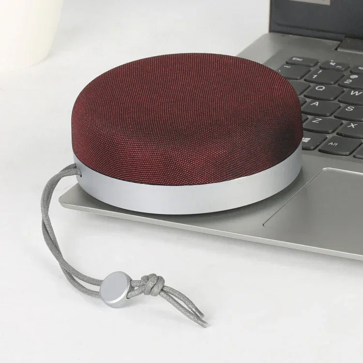 Red cloth-covered Bluetooth speaker with hanging cord and silver base ring