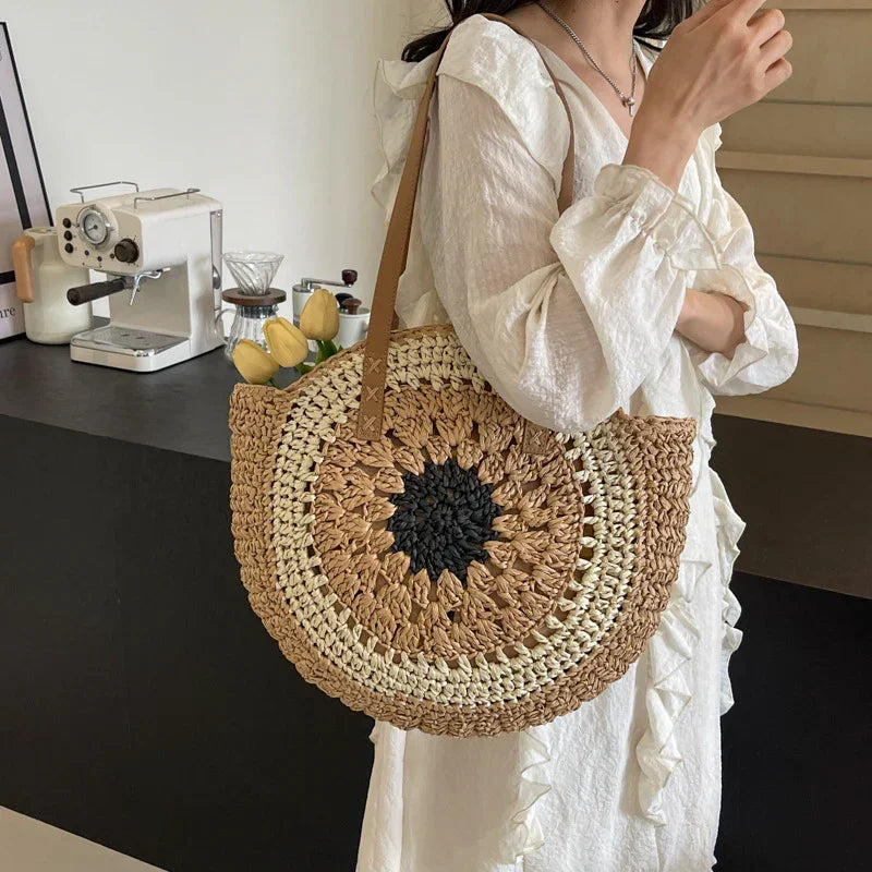 Crochet straw tote bag with dark round floral center and brown leather handles