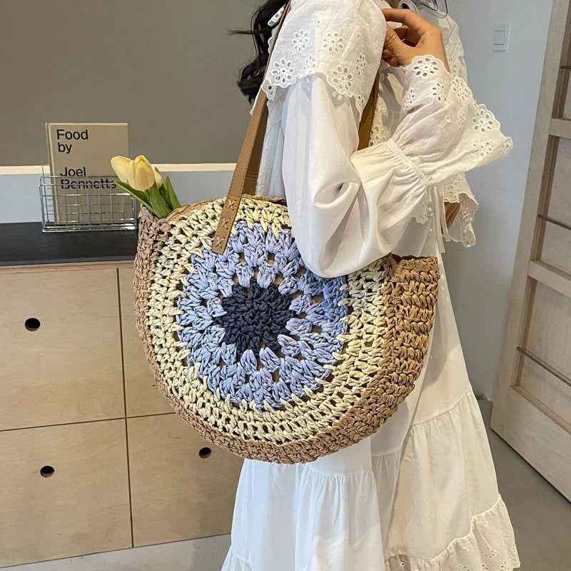 Crochet straw tote bag with blue round floral center and brown leather handles