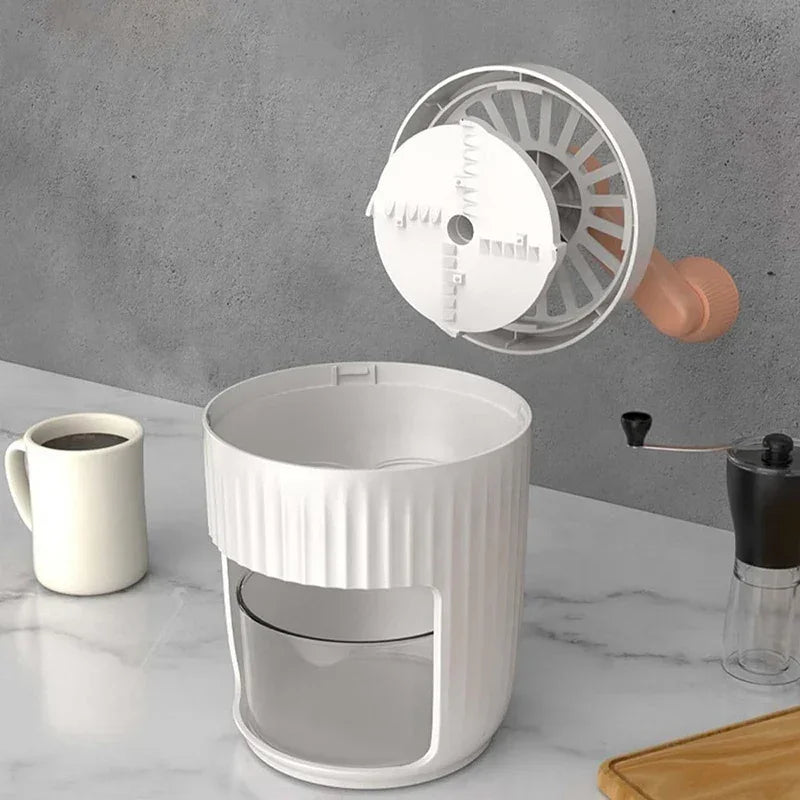 Hand-cranked ice crusher with orange side knob, open top showing ice-shaving disc