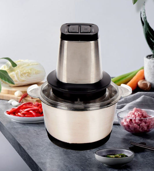 Stainless steel food processor on a kitchen counter with ingredients.  YAXSO STORE UAE