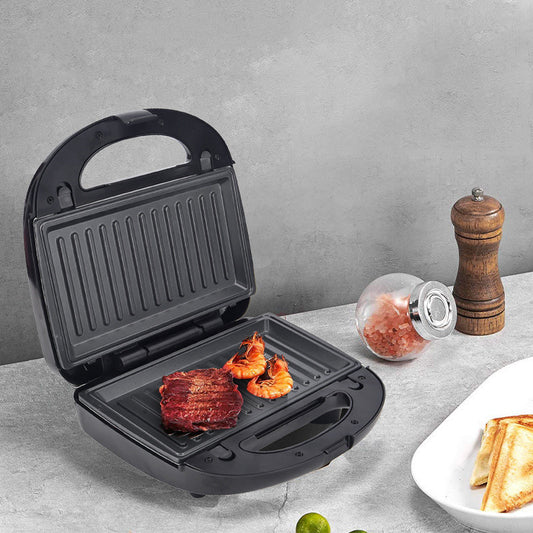 Black sandwich press with food on a gray surface