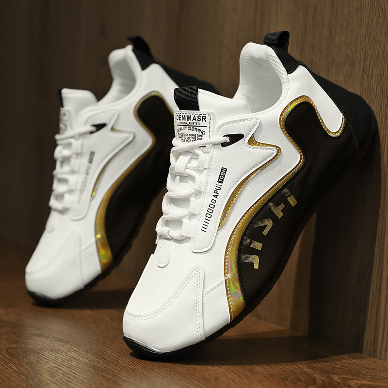 Pair of white and black lace-up sneakers with gold trim and logo patches on wood
