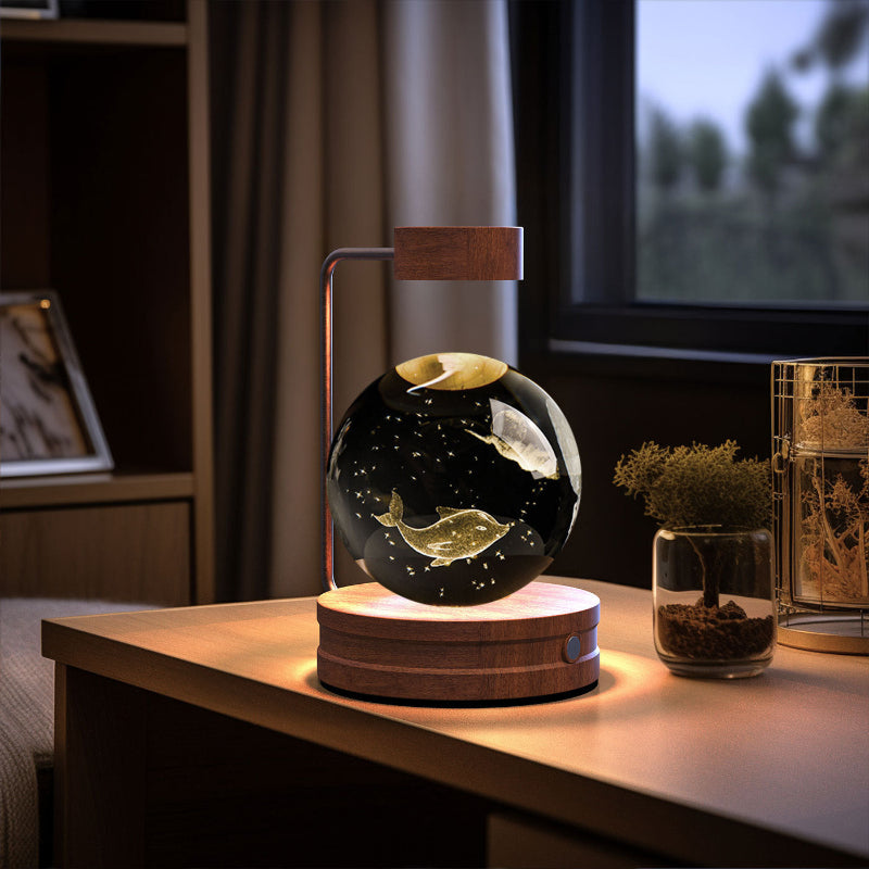 Glowing crystal-ball LED night light with warm light in clear globe and round wooden base.