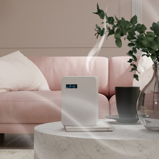 Air purifier on a marble table with a pink sofa and plant in the background