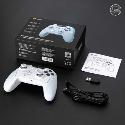 White gaming controller with packaging, USB cable, and manual on a dark surface