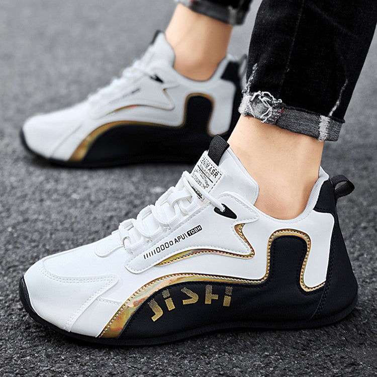 Lace-up sneakers in white with black panels and gold trim, worn on gray ground