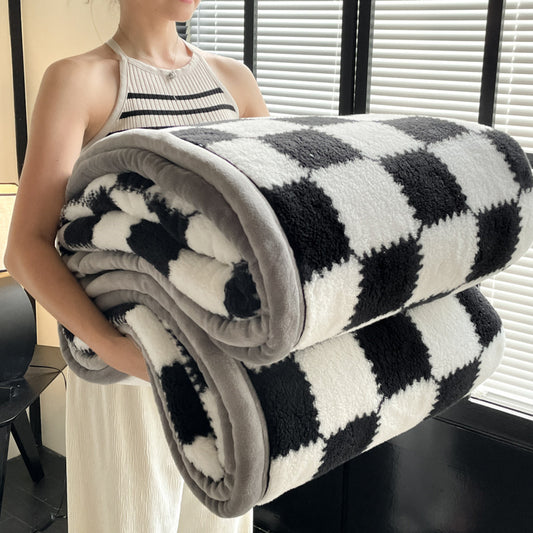 Person holding a black and white checkered blanket indoors.