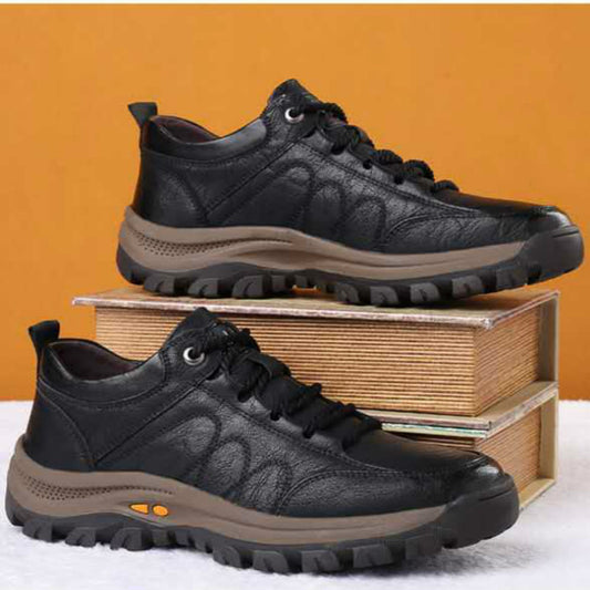 Black leather shoes with brown soles on a white surface and orange background