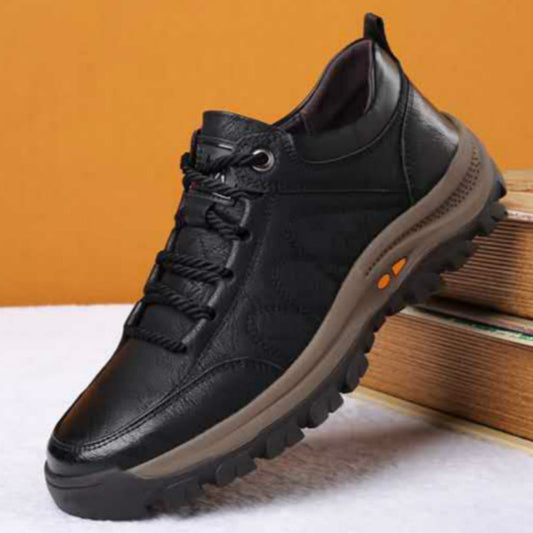 Black leather shoe with brown sole on a white surface with orange background