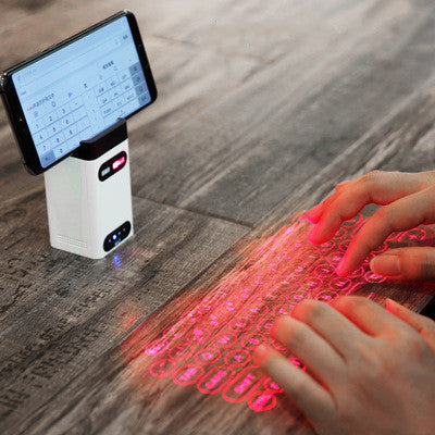 White laser projector keyboard displaying red key icons on a wooden desk