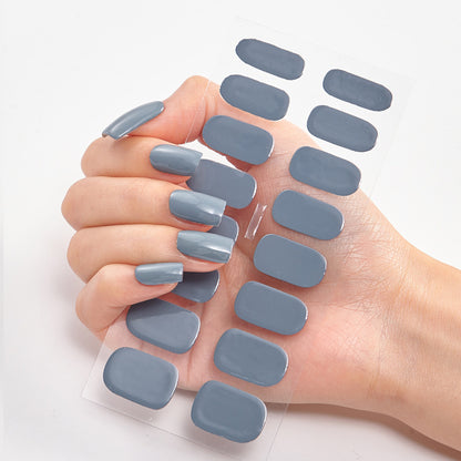 Hand with gray nail polish and additional gray nail pads on a white background