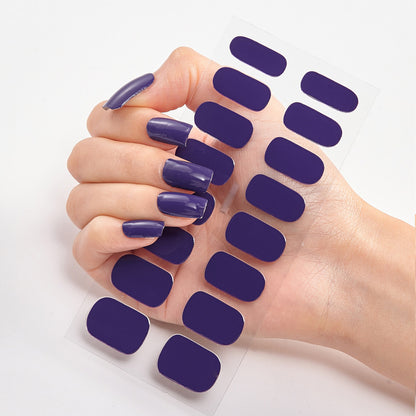 Hand with purple nail polish on nails and matching nail patches on a white background