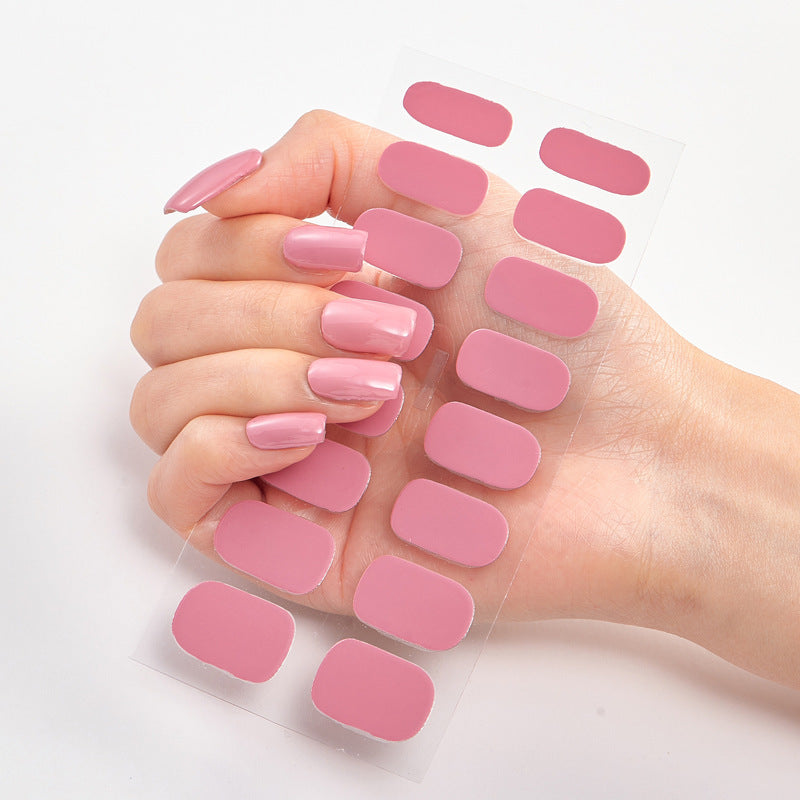 Hand with pink nail polish and additional nail pads on a light background