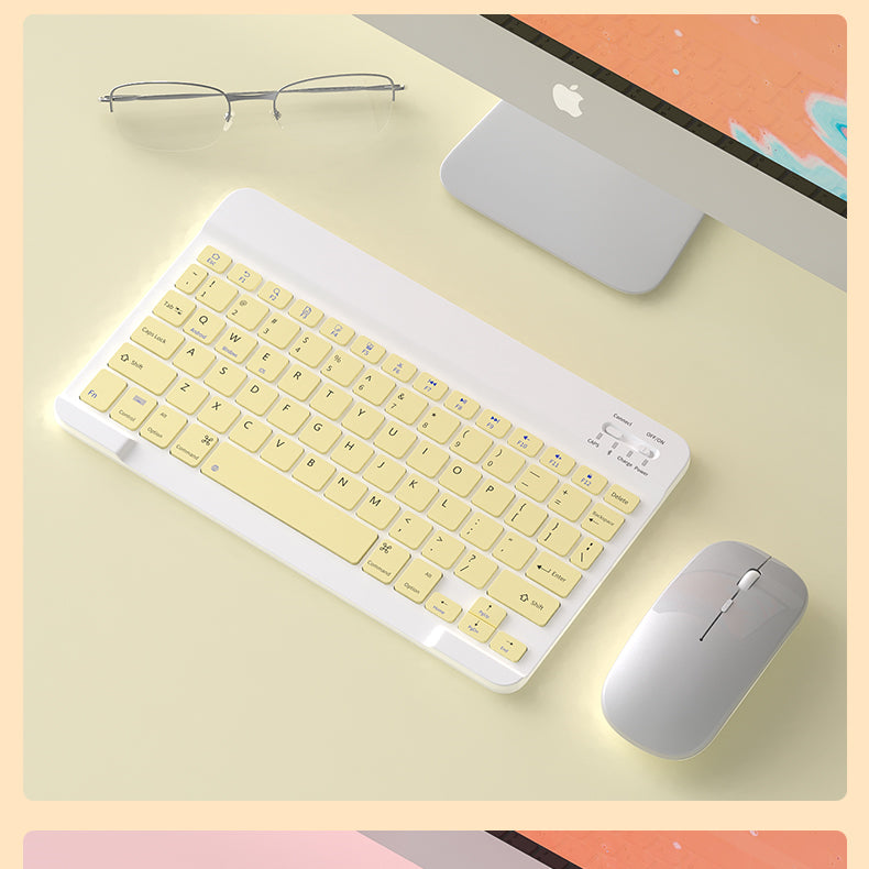 Yellow keyboard and mouse set on a desk with an Apple computer in the background
