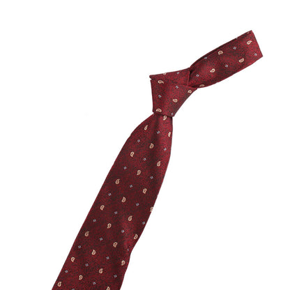 Red patterned tie with a gold violin-shaped pin and a small decorative item on a white background.