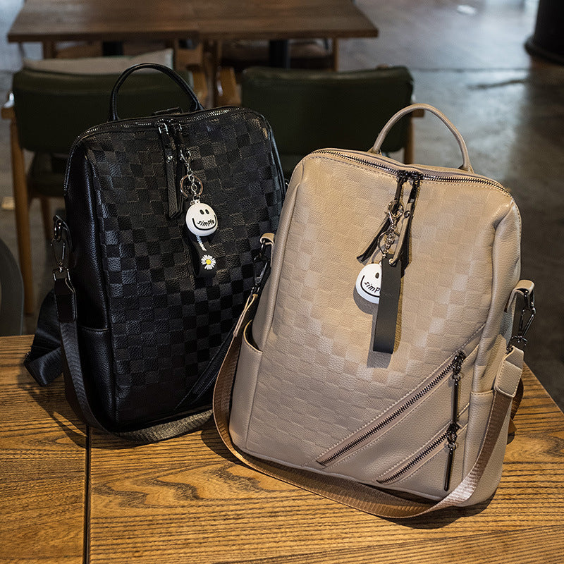 Two backpacks, one black checkered and one beige, on a wooden table.