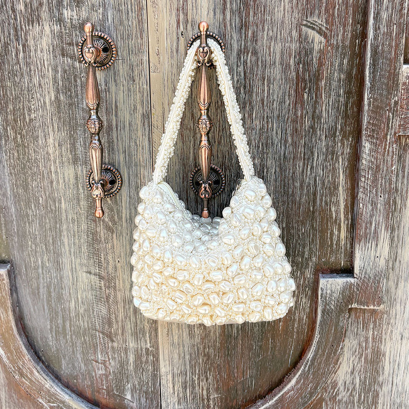 White pearl-beaded evening handbag with short top handle and visible interior lining