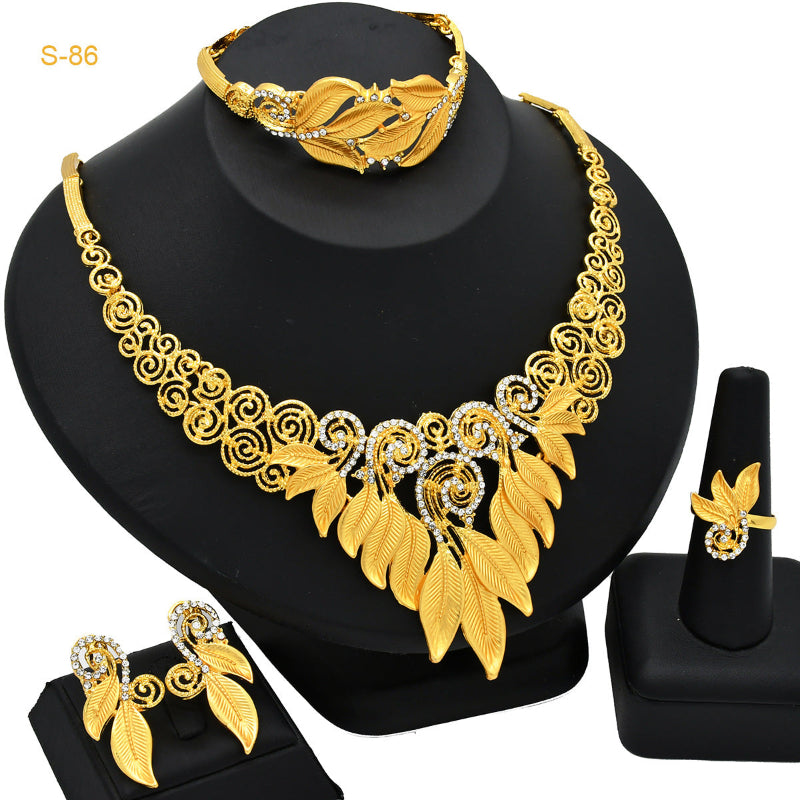 Gold jewelry set including necklace, bracelet, ring, and earrings on a black stand.