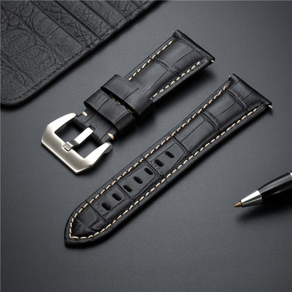 Black leather watch strap with metal buckle and tan edge stitching.