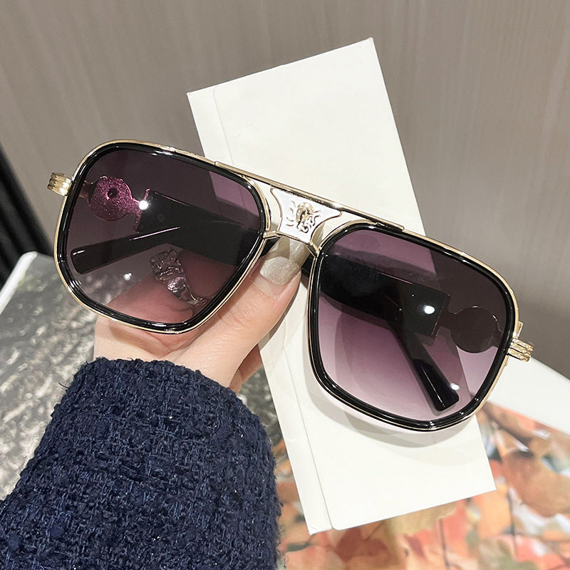 Oversized unisex sunglasses with dark purple lenses, gold-tone rims and decorative hinge details