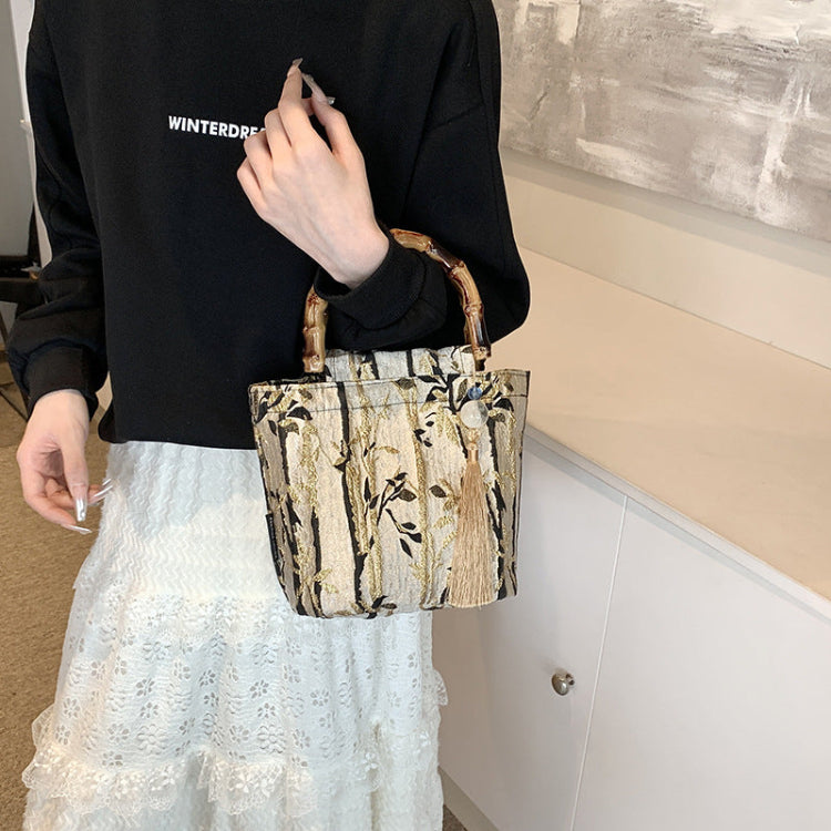 Person holding a patterned handbag with a black top and white lace skirt.