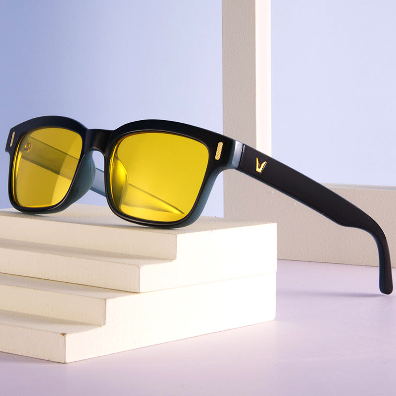 Sunglasses with yellow lenses and black frames on a stack of books with a light blue background