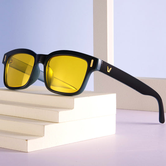 Sunglasses with yellow lenses and black frames on a stack of books with a light blue background