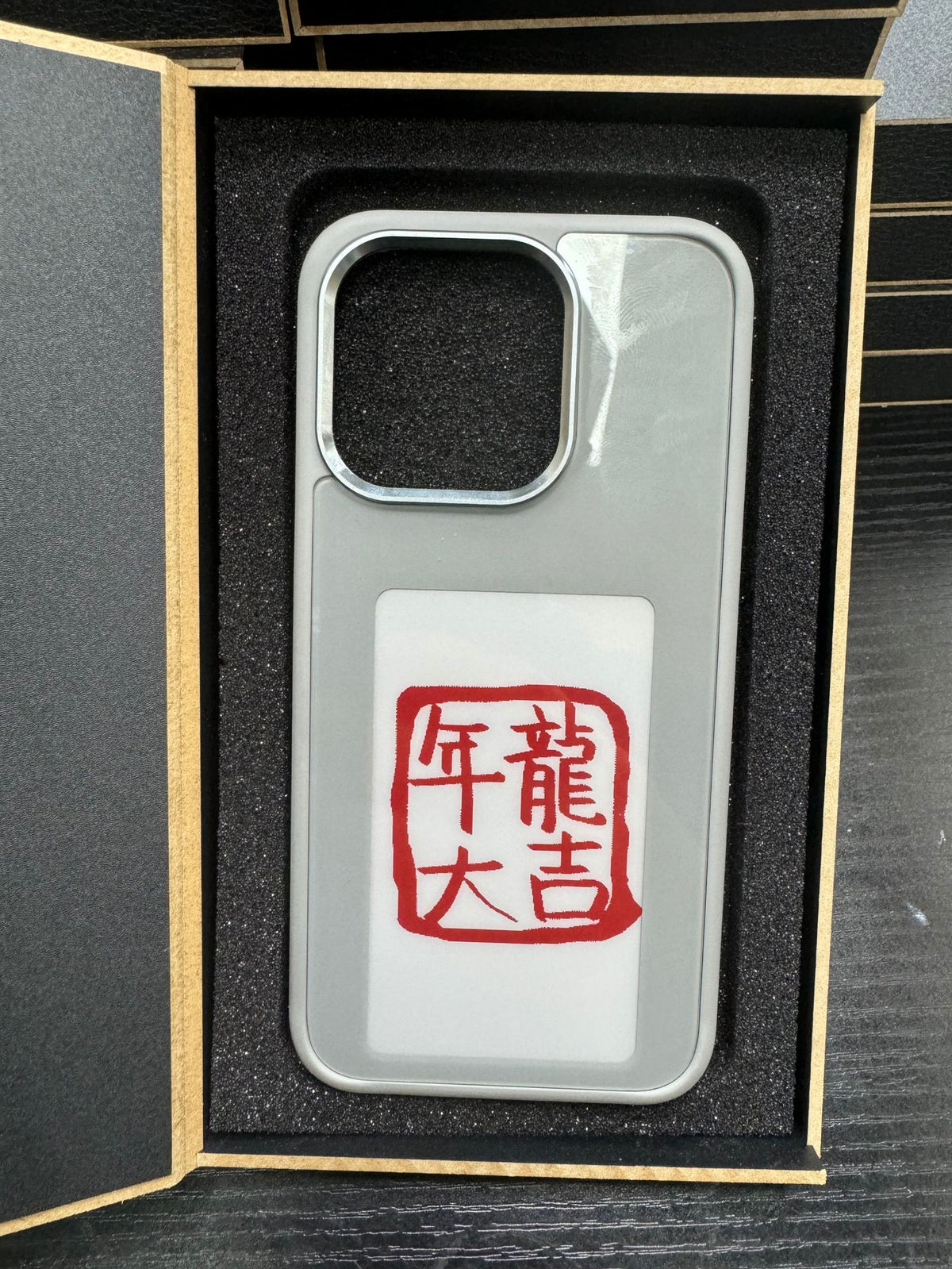 E-ink smart display phone case in box, light gray back with red character e-ink display
