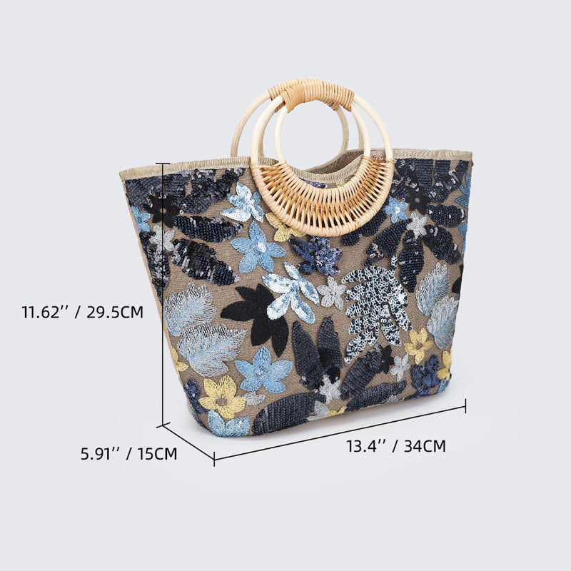Large woven cotton tote bag with navy-blue sequined florals and rattan half-moon handle