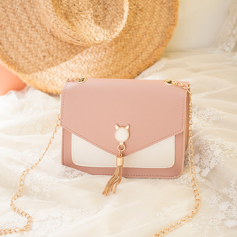 Small square PU leather crossbody bag with flap, tassel chain, blush pink and white panels.