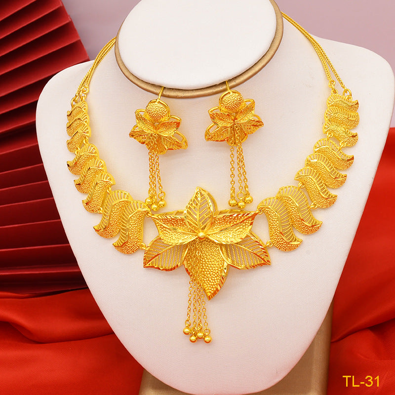 Gold necklace and earrings set on a white stand with red background