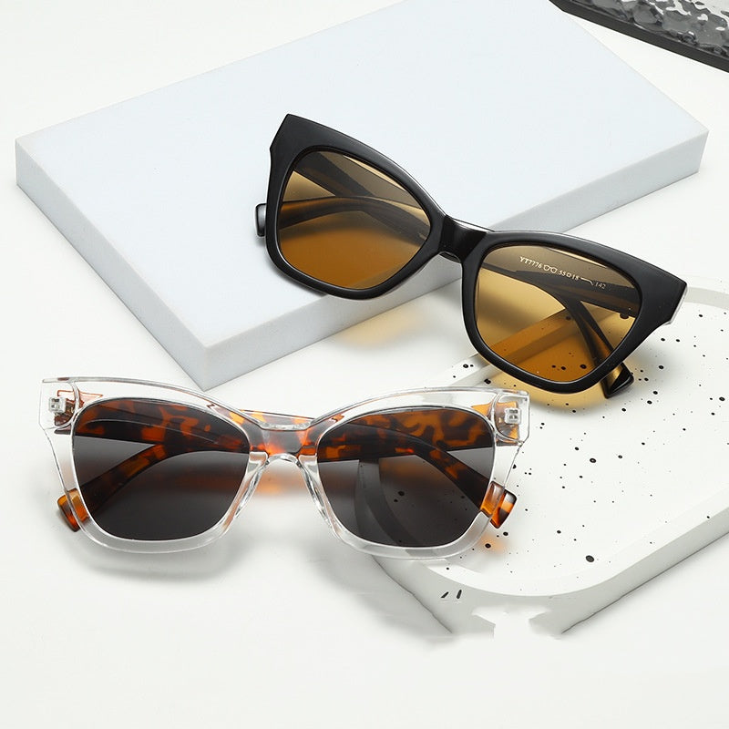 Black cat-eye sunglasses with amber-tinted lenses and thick angular frames